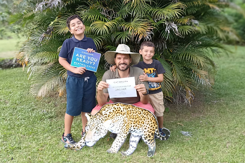 "Family holding sign with jaguar cutout"