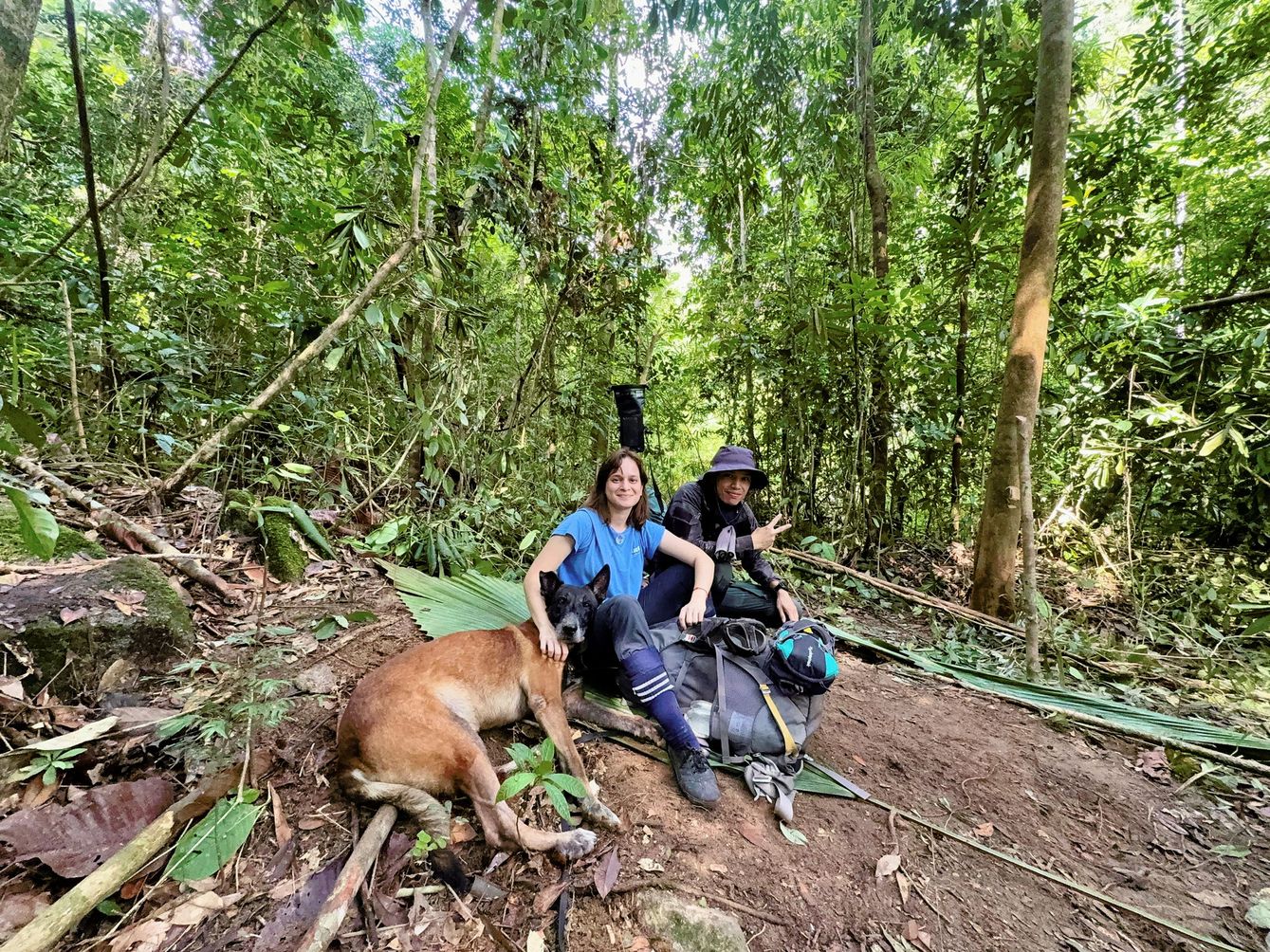 Dog and two people sit on the ground