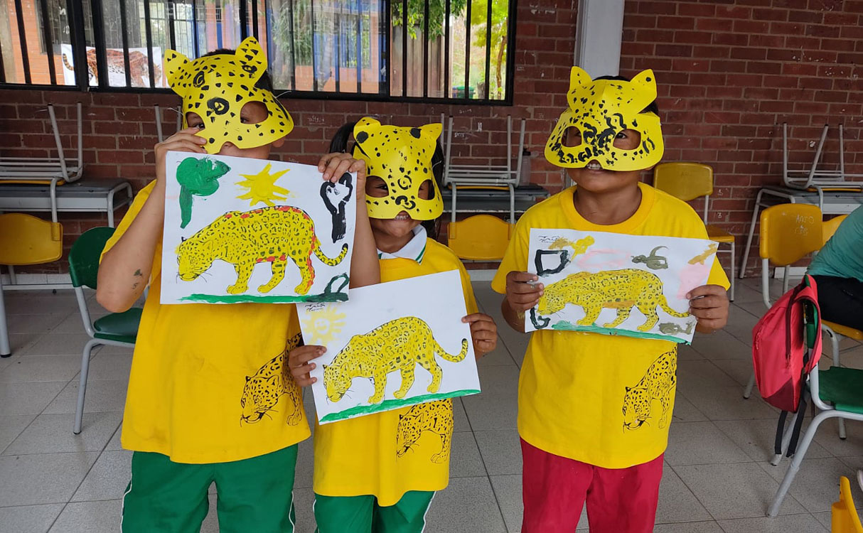 Students wearing cat masks and holding jaguar drawings they've made